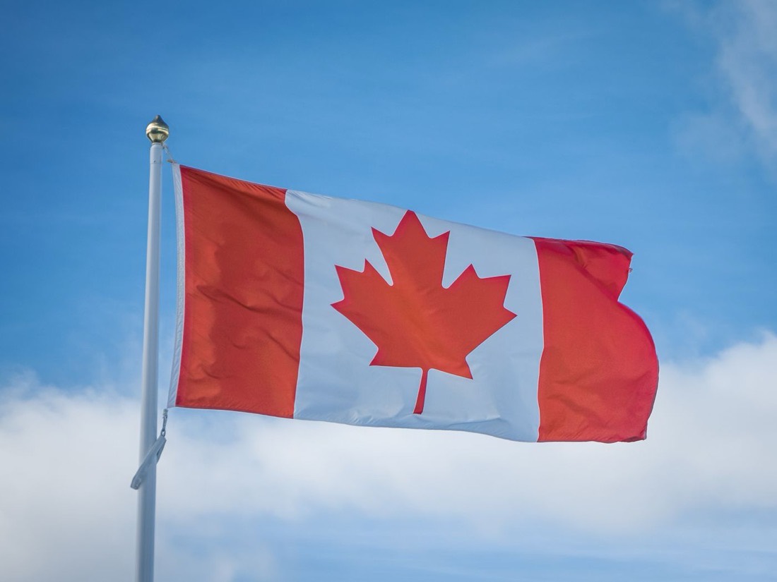 A Canadian flag flying against a clear sky